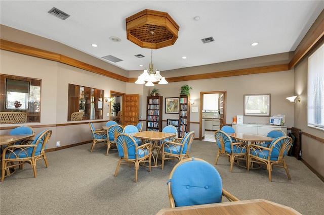 carpeted dining room with visible vents, baseboards, and a notable chandelier