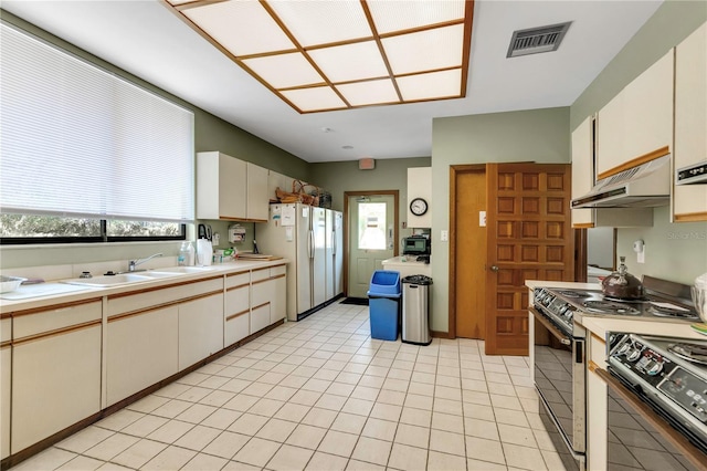 kitchen featuring electric range, visible vents, under cabinet range hood, a sink, and freestanding refrigerator