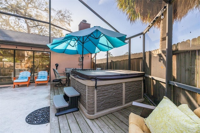 deck with a lanai, a fenced backyard, and a hot tub