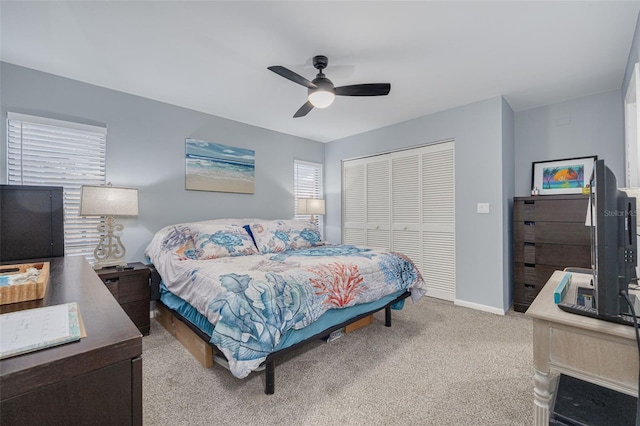 carpeted bedroom with a closet, baseboards, and ceiling fan