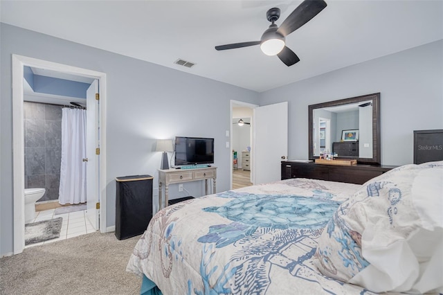 carpeted bedroom with visible vents, baseboards, ensuite bathroom, and a ceiling fan