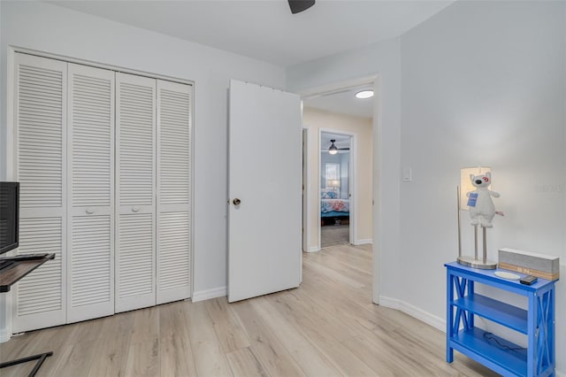 bedroom with a closet, a ceiling fan, light wood-type flooring, and baseboards