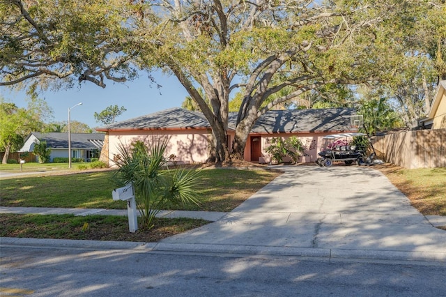 view of front of home with concrete driveway, a front yard, and fence