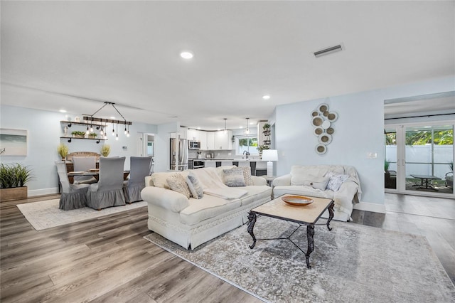 living room with visible vents, recessed lighting, baseboards, and wood finished floors