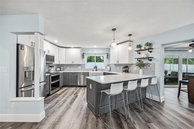 kitchen with tasteful backsplash, a kitchen breakfast bar, appliances with stainless steel finishes, and a peninsula