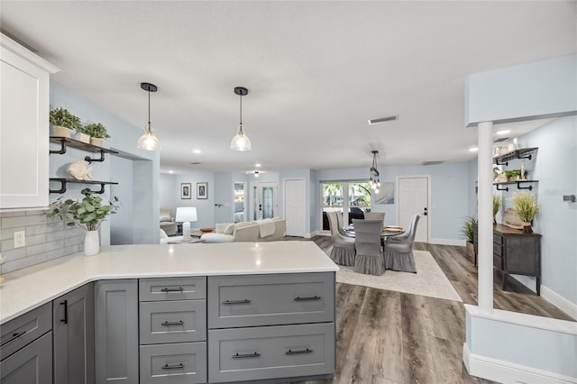 kitchen with visible vents, a peninsula, gray cabinets, dark wood-type flooring, and tasteful backsplash