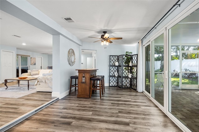 sitting room with ceiling fan, visible vents, baseboards, and wood finished floors