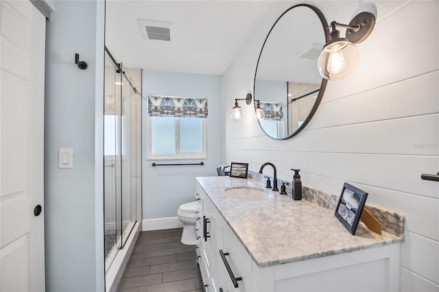 full bathroom featuring vanity, a shower stall, toilet, and visible vents