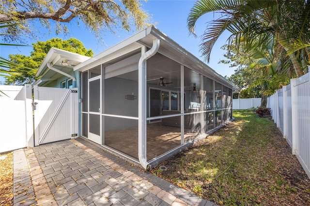 view of home's exterior with a patio area, a sunroom, a fenced backyard, and a gate