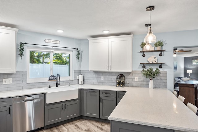 kitchen with gray cabinetry, dishwasher, decorative backsplash, a peninsula, and a sink