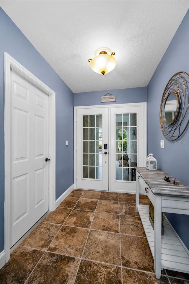 doorway featuring french doors, a textured ceiling, stone finish flooring, and baseboards