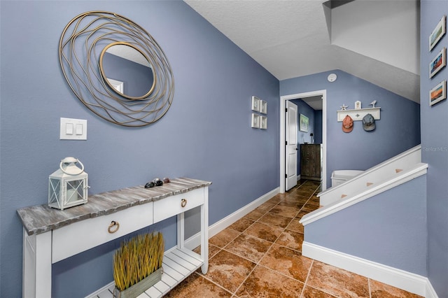 corridor with a textured ceiling, baseboards, and vaulted ceiling