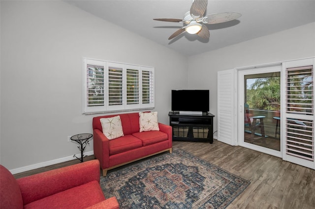 living area with baseboards, lofted ceiling, wood finished floors, and a ceiling fan