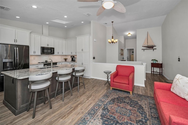 kitchen featuring visible vents, white cabinetry, black microwave, and a sink