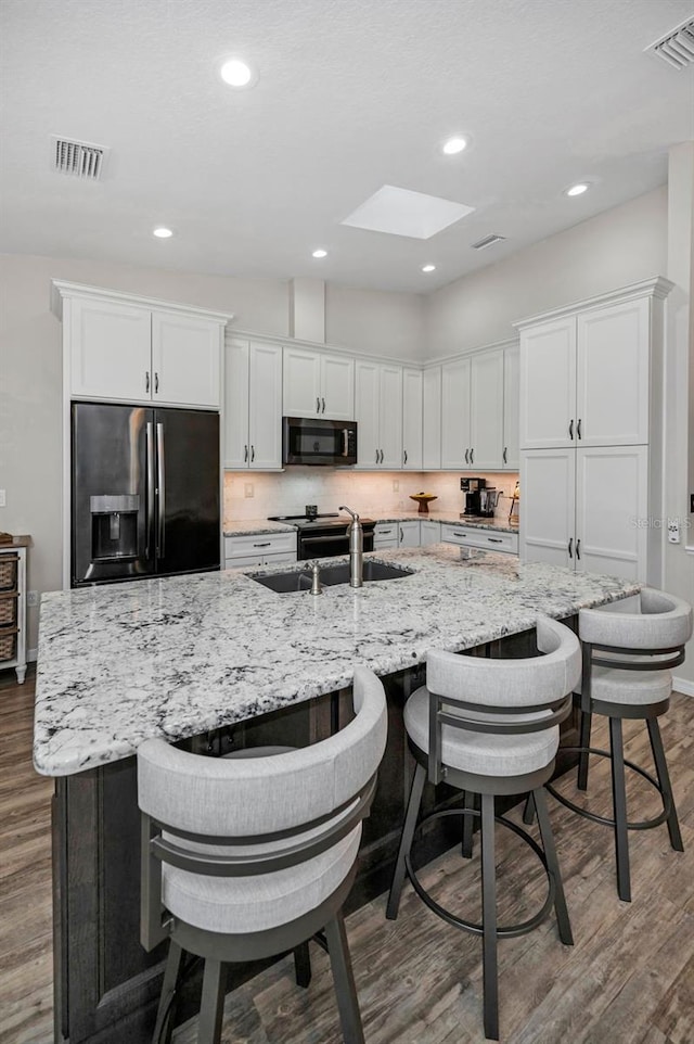 kitchen featuring visible vents, white cabinets, stainless steel refrigerator with ice dispenser, and wood finished floors