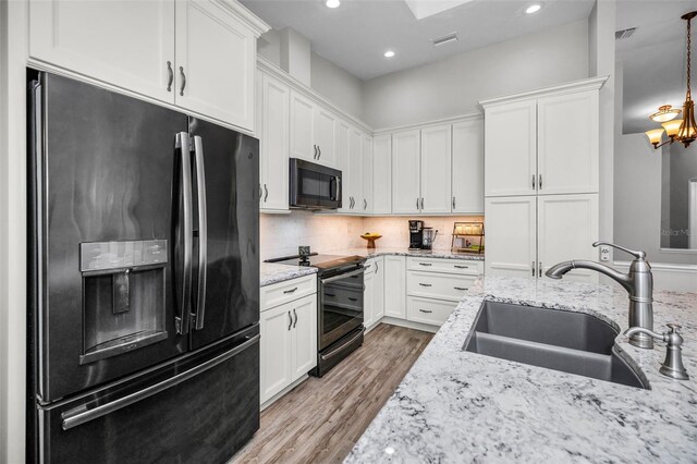 kitchen featuring visible vents, backsplash, white cabinets, black appliances, and a sink