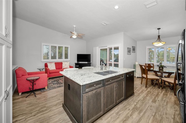 kitchen featuring a sink, visible vents, dark brown cabinetry, and light wood finished floors