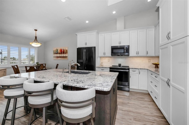 kitchen featuring visible vents, backsplash, white cabinets, stainless steel appliances, and a sink