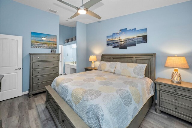 bedroom with visible vents, ensuite bath, wood finished floors, and a ceiling fan