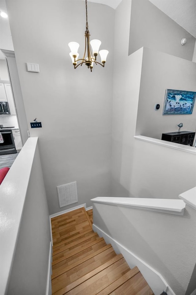 stairs featuring wood finished floors, visible vents, and baseboards