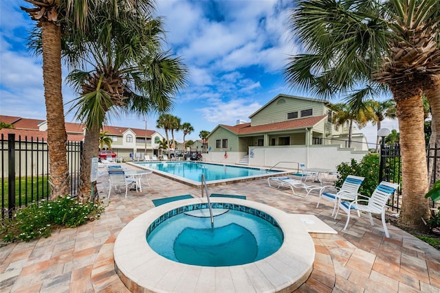 pool featuring a community hot tub, a patio, and fence