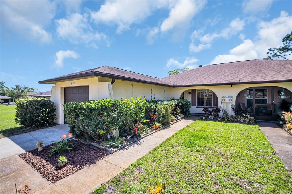 3479 Maclaren Dr, Palm Harbor, FL 34684 - ranch-style house with a garage, stucco siding, concrete driveway, and a front yard