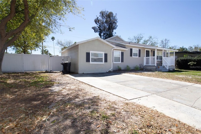 ranch-style home with fence, covered porch, and driveway