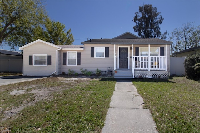 view of front facade with covered porch, a front lawn, and fence