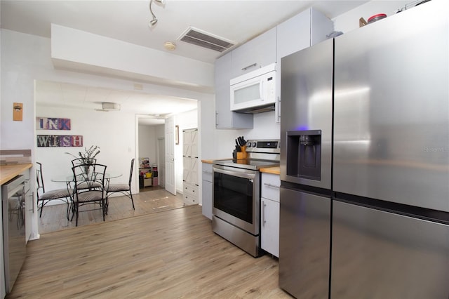 kitchen featuring visible vents, light wood-style flooring, wood counters, stainless steel appliances, and white cabinets