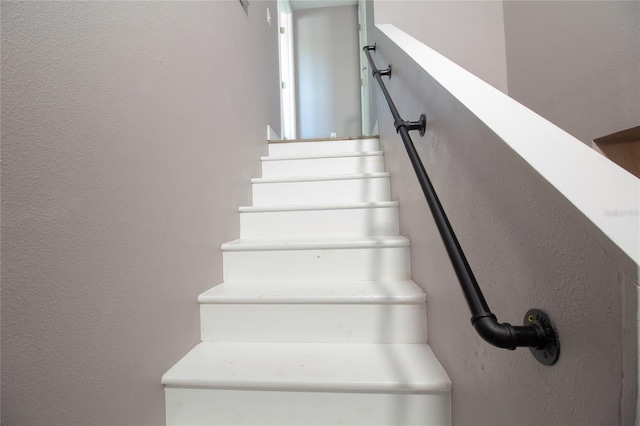 stairway featuring a textured wall