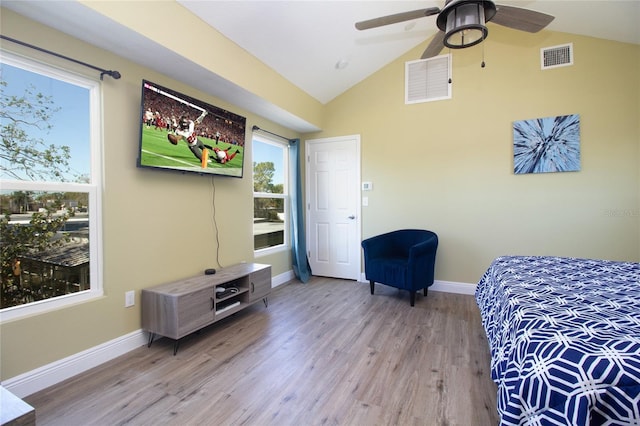 bedroom featuring visible vents, baseboards, light wood-style floors, and vaulted ceiling