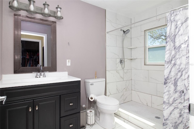 bathroom featuring tiled shower, toilet, and vanity