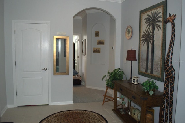 corridor with tile patterned flooring, baseboards, and arched walkways