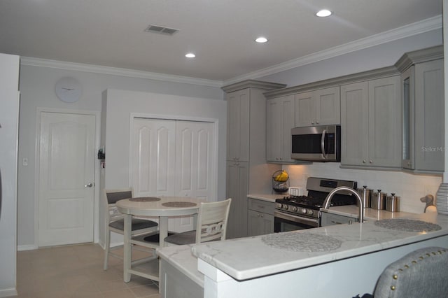 kitchen featuring visible vents, gray cabinets, stainless steel appliances, and ornamental molding