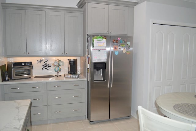 kitchen featuring light tile patterned floors, decorative backsplash, stainless steel fridge, and gray cabinets