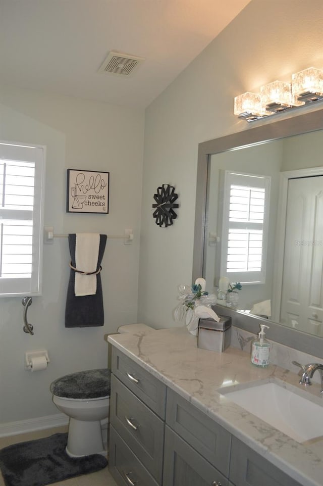 bathroom with visible vents, toilet, vanity, and baseboards