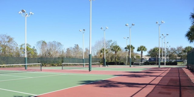 view of tennis court featuring community basketball court and fence