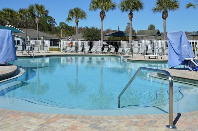 pool with a patio, a water slide, and fence