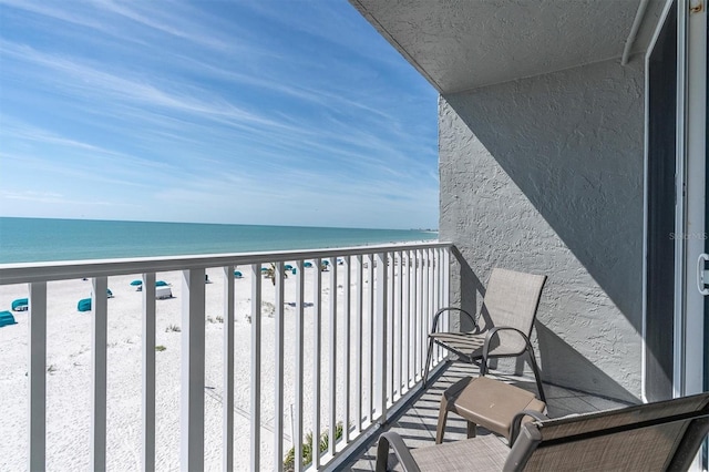 balcony featuring a view of the beach and a water view