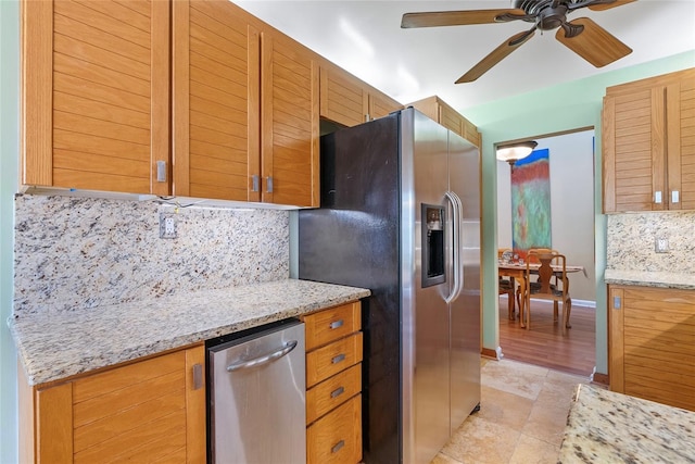 kitchen featuring a ceiling fan, appliances with stainless steel finishes, decorative backsplash, baseboards, and light stone countertops