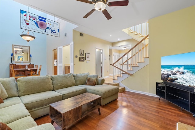 living room with a ceiling fan, stairs, baseboards, and wood finished floors