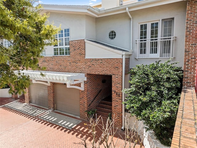 view of front of house featuring decorative driveway, brick siding, and stucco siding