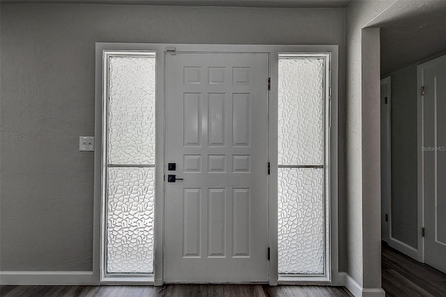 interior space featuring baseboards, dark wood-style flooring, and a textured wall