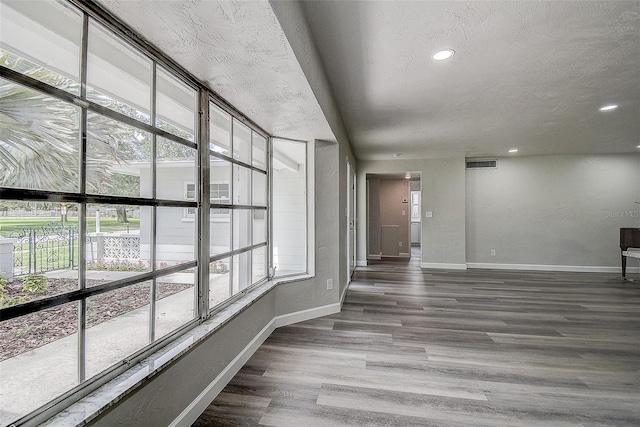 interior space with wood finished floors, baseboards, visible vents, and a wealth of natural light