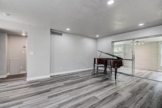 spare room featuring visible vents, a textured ceiling, wood finished floors, recessed lighting, and baseboards