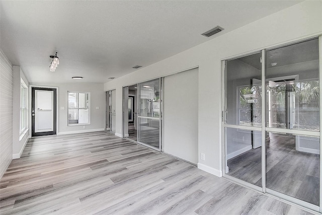 spare room featuring visible vents, baseboards, a textured ceiling, and wood finished floors