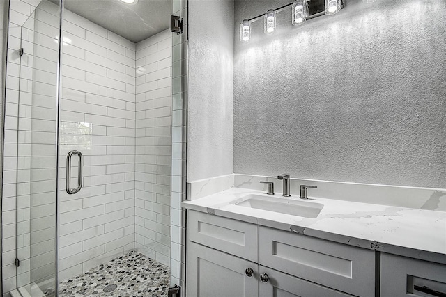 full bath with a shower stall, a textured wall, and a sink