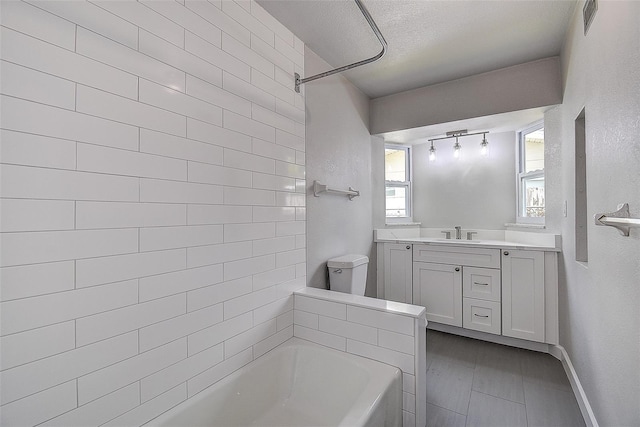 bathroom with vanity, a tub to relax in, baseboards, walk in shower, and a textured ceiling