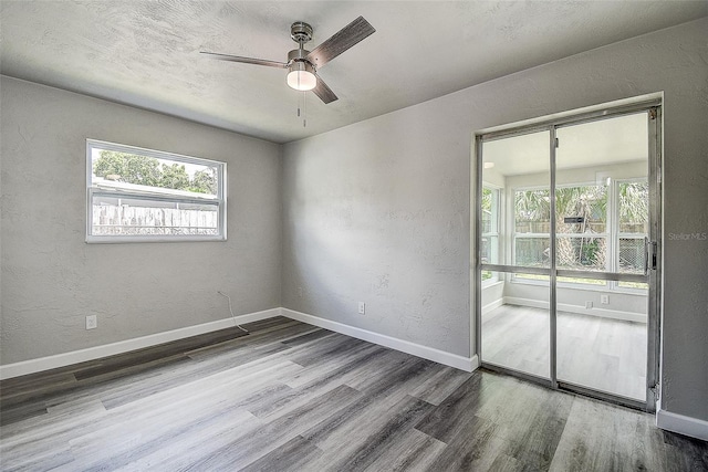 unfurnished room with wood finished floors, baseboards, and a textured wall