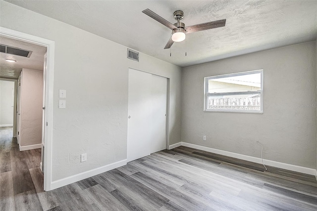 unfurnished bedroom featuring visible vents, baseboards, a closet, and wood finished floors